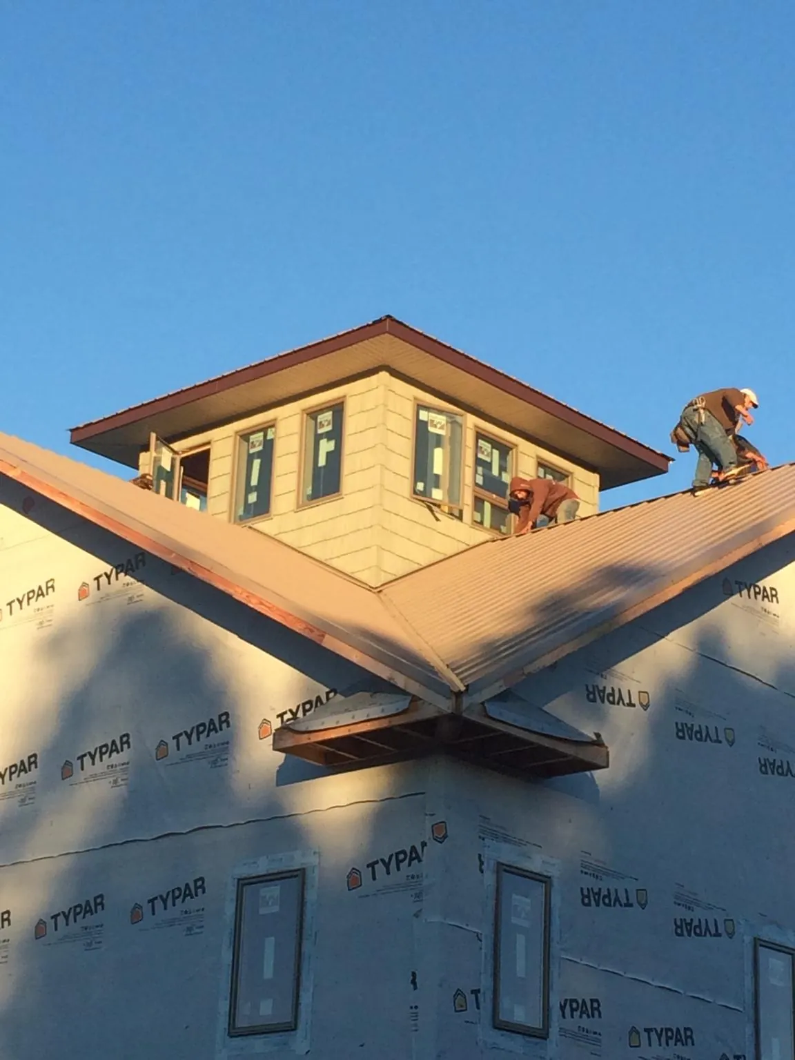 Roofers working around a rooftop cupola on a new metal roof at sunset — Roof Waterproofing in Newburg by Roofing Brothers